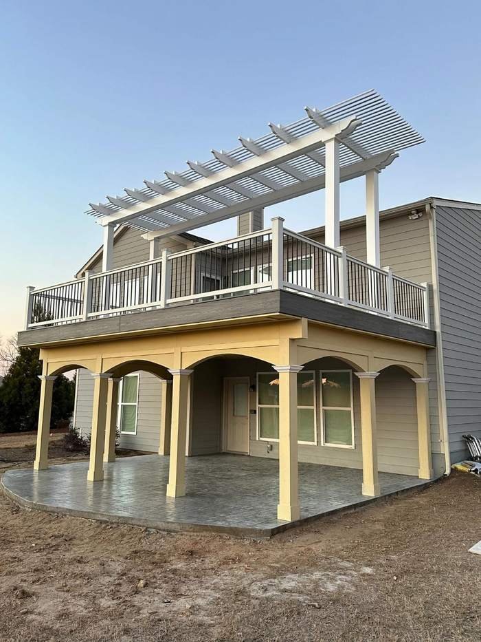 White pergola over an upper deck with arched columns below