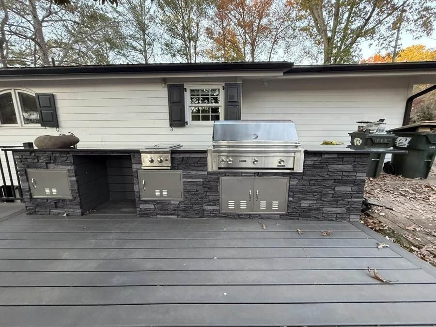 Stone outdoor kitchen with built-in grill on a composite deck
